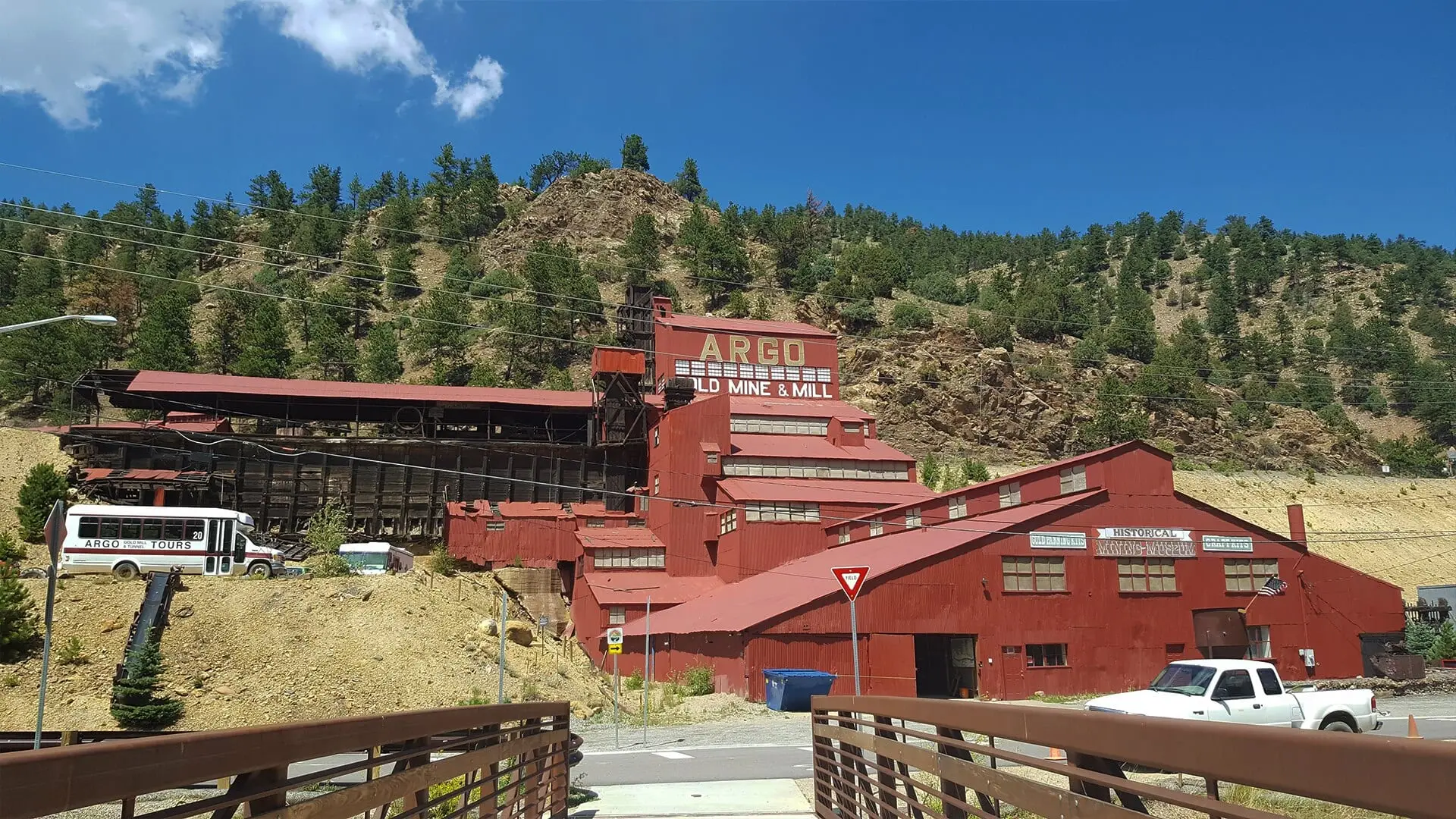 The red Argo gold mill on the hillside above Idaho Springs, its name painted high on the mill, under a blue sky